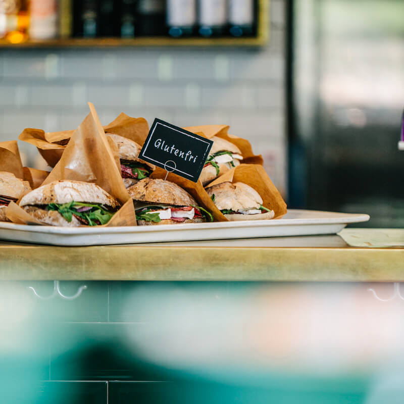 fyllda frallor i pappersomslag som ligger på en bricka samt en skylt med texten "Glutenfri"