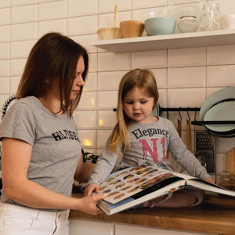 ung kvinna och flicka läser en bok i köket